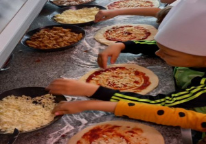 Dzieci dekorują pizzę ulubionymi składnikami