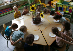 Dzieci siedząc przy stole zlizują miód z talerzyków.
