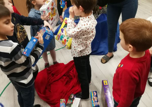 Dzieci oglądają prezenty , które zostawił dla nich pod choinką Mikołaj.