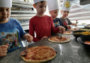 Dzieci samodzielnie przygotowują pizzę.