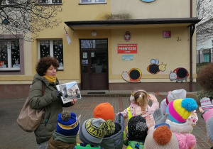Dzieci stoją przed Przedszkolem Miejskim Nr 8 "Promyczek".