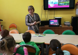 Dzieci patrzą na ekran telewizora, na którym są fotografie różnych miejsc w Kutnie.