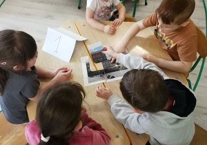 Dzieci układają zdjęcie obiektu z pociętych elementów.
