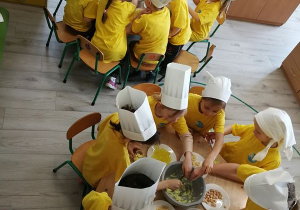 Dzieci przy stolikach samodzielnie przygotowują swoje słoneczne deserki.