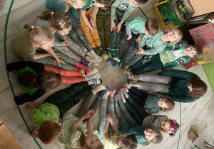 Dzieci i pani Beatka siedzą w kręgu i prezentują swoje kolorowe skarpetki nie do pary.