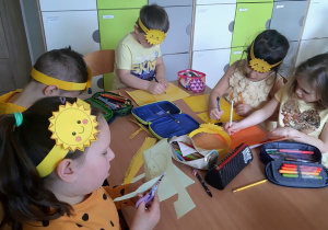 Dzieci siedzą przy stolikach i rysują elementy do plakatu.