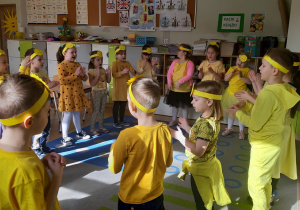 Dzieci ustawione w kole tańczą i śpiewają piosenkę.