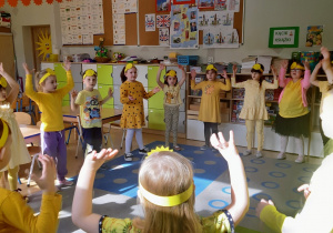 Dzieci ustawione w kole tańczą i śpiewają piosenkę.