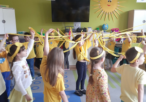 Zabawa z wykorzystaniem hula-hop i paskami bibuły w kolorze żółtym przy piosence pt. Promyk słońca.