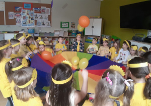 Zabawy z chustą animacyjną i balonami w kolorach żółtym i pomarańczowym.