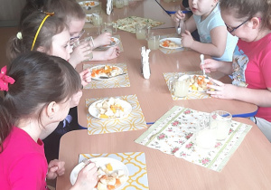 Dzieci degustują sałatkę z żółtych owoców i lemoniadę cytrynową.