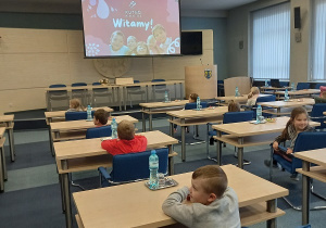 dzieci siedzą przy stolikach na sali konferencyjnej i rozwiązują quiz na temat miasta Kutno.