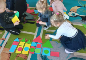 Dzieci układają zamek z figur geometrycznych wg. instrukcji