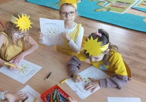 Dzieci prezentują wykonana kartę pracy ze słońcem w roli głównej