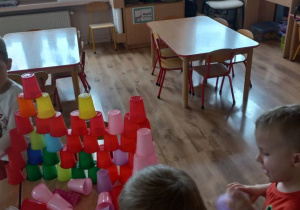 Dzieci układają jak najwyższą budowlę z kolorowych kubków