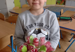 Natan prezentuje bukiet z lizaków - róż, zrobionych przez dzieci