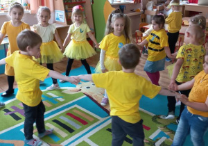 Dzieci trzymają się za ręce, tańczą i śpiewają, wybierają Królową Pszczół