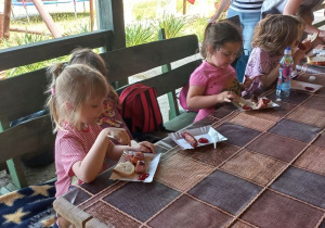 Dzieci jedzą grillowane kiełbaski na drugie danie