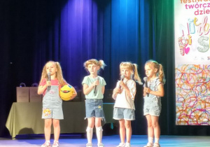 Lucynka śpiewa piosenkę, obok stoi Maja, Zosia i Emilka