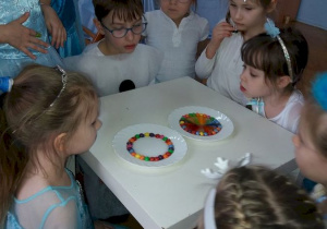 Dzieci podziwiają tęczę z kolorowych cukierków