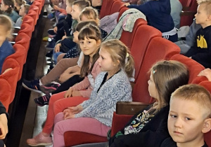 Dzieci siedzą na widowni i czekają na spektakl.