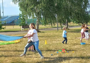 Zabawy ruchowe i sprawnościowe: Rodzice Weroniki przerzucają balon wypełniony wodą z jednego ręcznika na drugi, do innej pary, tak żeby nie spadł