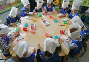 Dzieci ozdabiają ciastka w kształcie pierników.