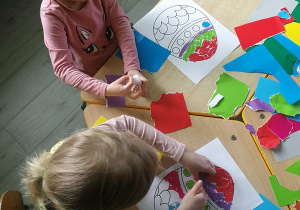 Dzieci wyklejają kolorowym papierem szablon pisanek wielkanocnych.