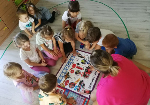 Dzieci omawiają akcesoria służb ratunkowych na podstawie plakatu.