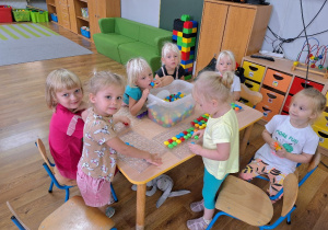 Dziewczynki bawią się układankami guziczkowymi przy stoliku.
