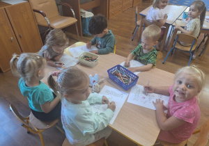 Dzieci kolorują obrazki konturowe tematycznie związane z Dniem Chłopca.