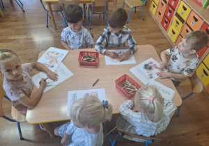 Dzieci kolorują obrazki konturowe tematycznie związane z Dniem Chłopca.