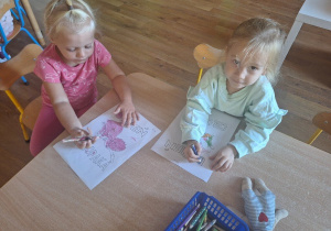Dziewczynki kolorują obrazki konturowe tematycznie związane z Dniem Chłopca.