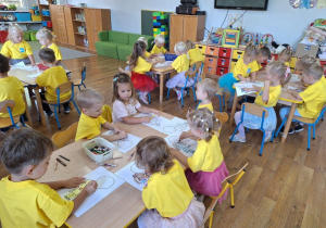 Dzieci wykonują przy stolikach pracę plastyczną związaną tematycznie z Dniem Przedszkolaka.