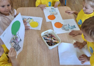 Dzieci wykonują przy stolikach pracę plastyczną związaną tematycznie z Dniem Przedszkolaka.