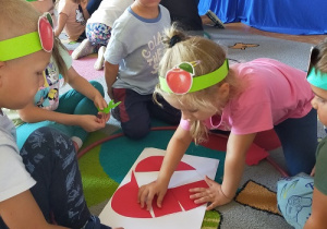 Dzieci układają puzzle czerwonego jabłka