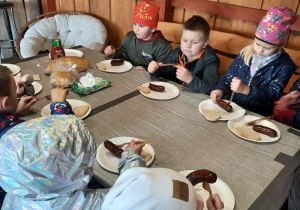 Dzieci jedzą upieczone kiełbaski