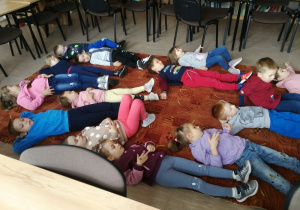 Dzieci leżą na dywanie.