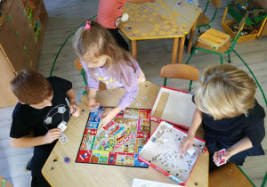 Dzieci przy stoliku grają w grę.