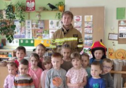 Dzieci z grupy Montessori pozują do wspólnego zdjęcia ze strażakiem