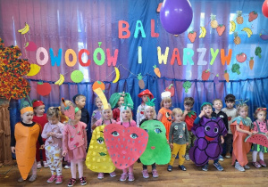 Dzieci przebrane w kolorowe stroje pozują do zdjęcia grupowego.