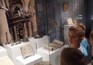Chłopcy oglądają dawne pisma umieszczone w gablocie