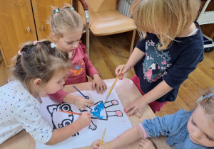 Dziewczynki malują farbami postać Kici Koci.