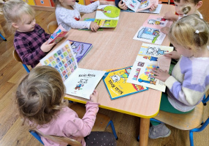 Dzieci oglądają książeczki, których bohaterką jest Kicia Kocia.