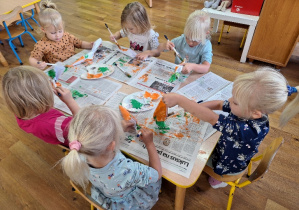 Dzieci malują farbami plakatowymi przestrzenne modele marchewek.