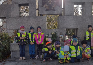 Dzieci pozują do wspólnego zdjęcia pod pomnikiem.