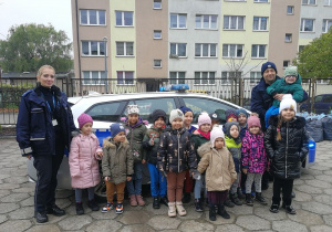 Dzieci wraz z policjantami pozują do zdjęcia na tle radiowozu.