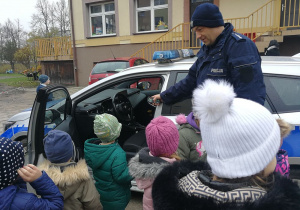 Policjant pokazuje dzieciom wnętrze radiowozu.
