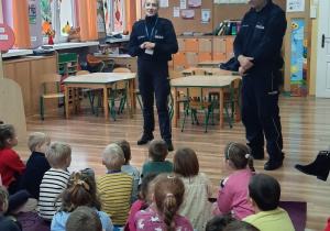 Pani policjantka i pan policjant rozmawiają z dziećmi na temat bezpiecznych i niebezpiecznych zachowań w różnych sytuacjach