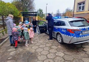 Policjant prezentuje dzieciom pojazd policyjny.